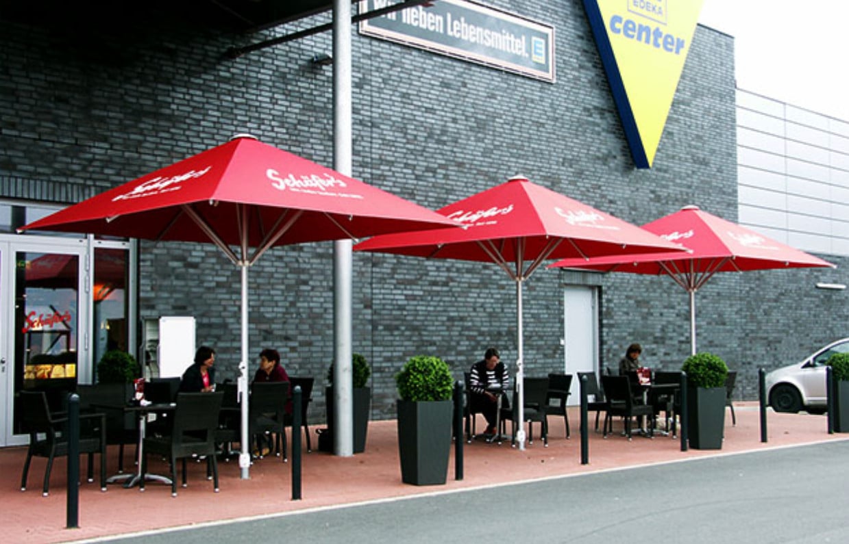 Rote Werbeschirme mit Schäfer's-Logo vor einem Bäckereieingang, ideal für Außenbereiche von Cafés und Bäckereien.