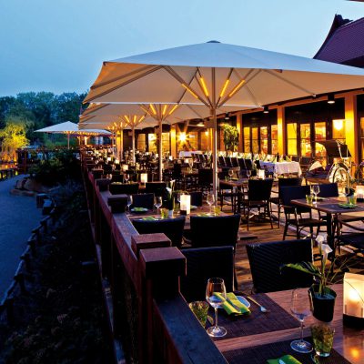 Beleuchtete Großschirme auf einer Restaurantterrasse bei Nacht mit stimmungsvoller Atmosphäre.